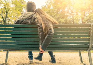 Couple on a bench - Two lovers sitting on a bench in a park and holding themselves by hands - Concepts of autumnlovetogethernessrelationship